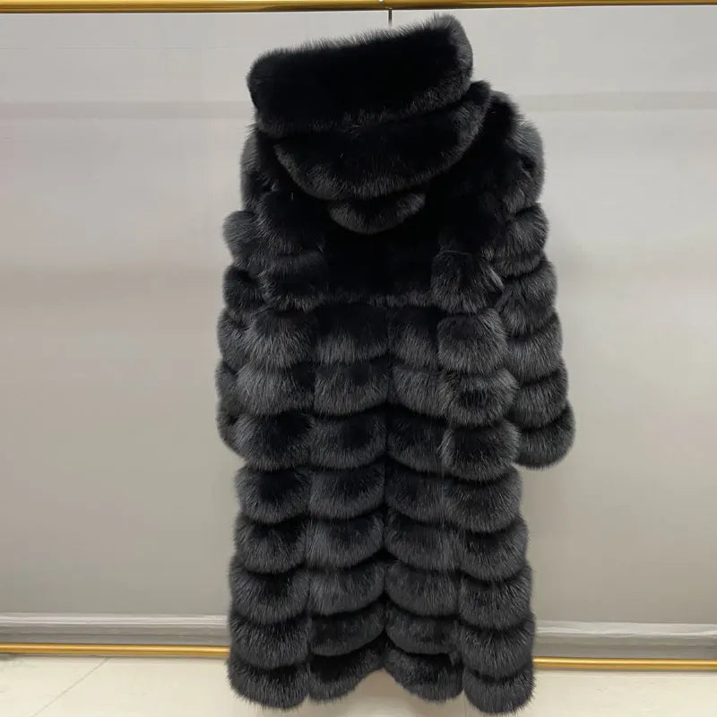 A long black fur coat with a high padded collar, hanging against a light gray wall.