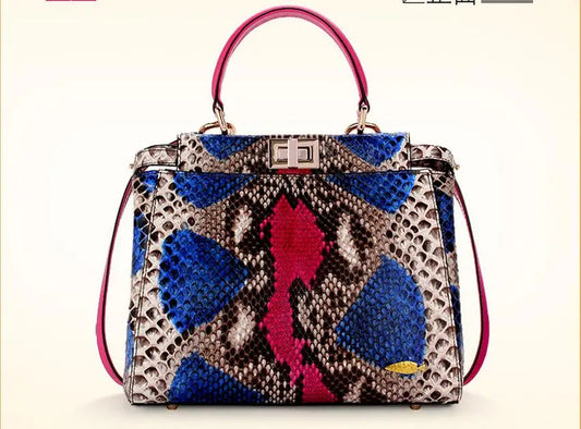 A structured handbag with a multicolor snakeskin pattern featuring blue, pink, brown, and beige tones, with magenta leather top handles and a silver-tone front clasp, set against a plain cream background.