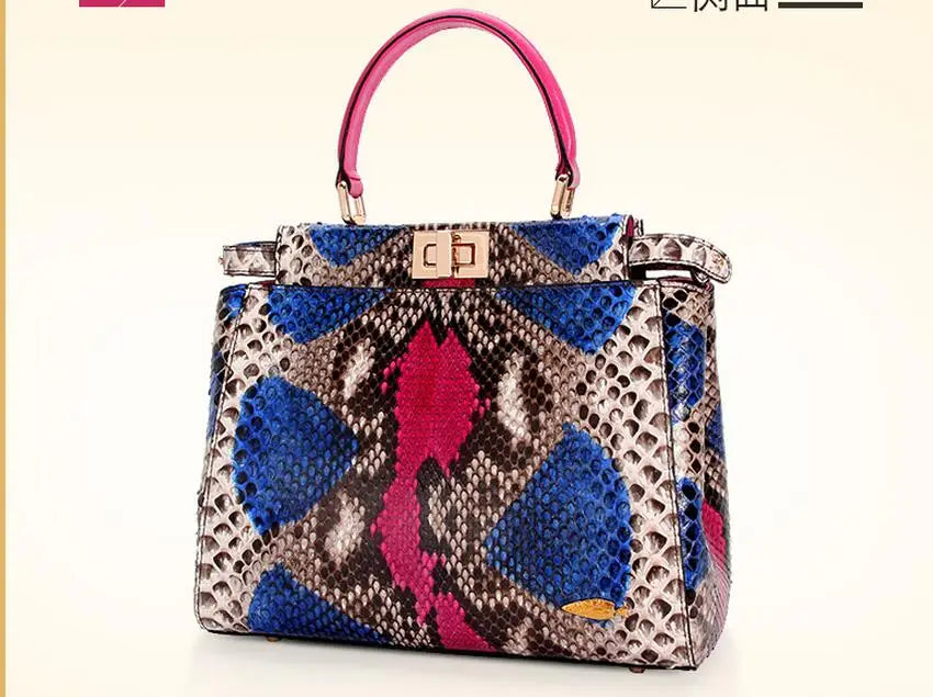 A structured handbag with a multicolor snakeskin pattern featuring blue, pink, gray, and beige tones, with a bright pink top handle and gold-tone hardware.