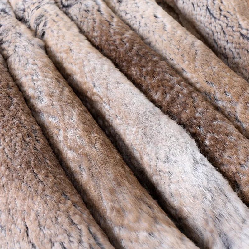 A close-up of several textured faux fur or rabbit fur strips in mixed natural tones, including beige, brown, gray, and cream, arranged diagonally.