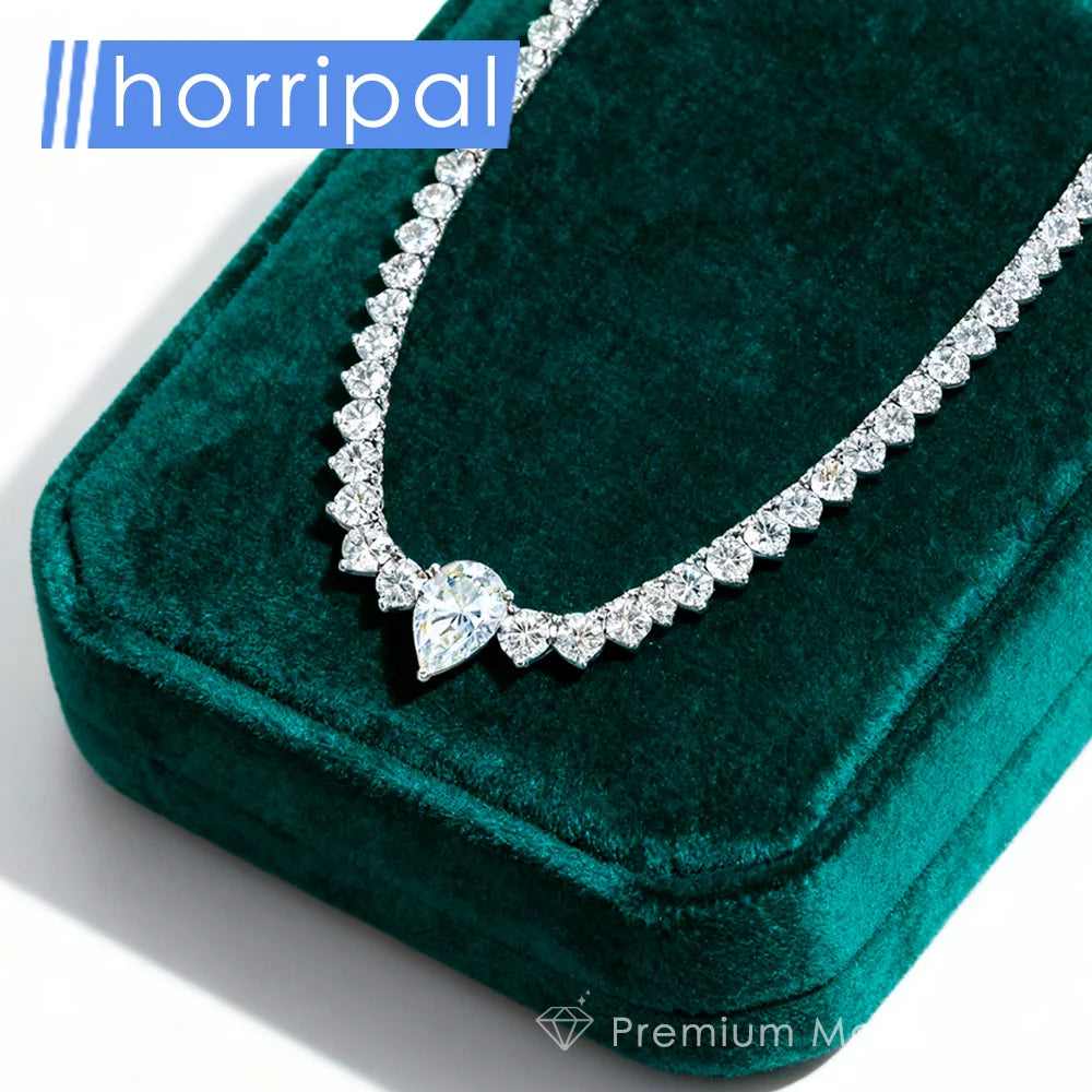 A sparkling diamond necklace with a pear-cut center stone and a repeating diamond border, displayed on a deep green velvet jewelry box. The brand name 'horripal' is visible in the top left corner.