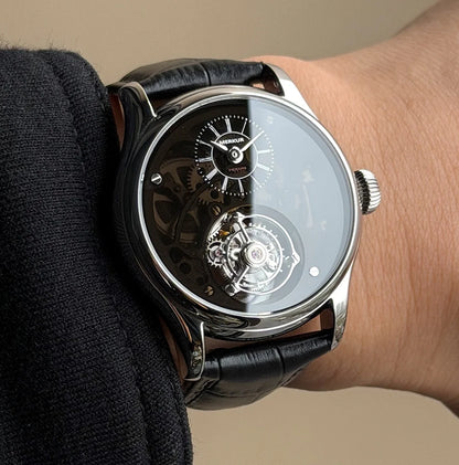 Luxury watch with black leather strap on a wrist against a neutral background