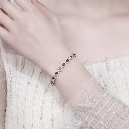 Bracelet with red gemstones on a person's wrist wearing a light dress.