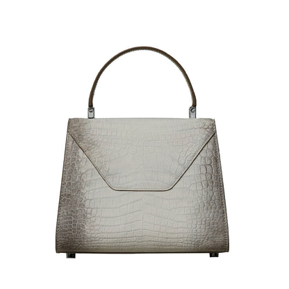 A structured handbag with a crocodile-embossed texture in a light taupe-gray color, featuring a top handle and silver-tone hardware, shown against a plain white background.