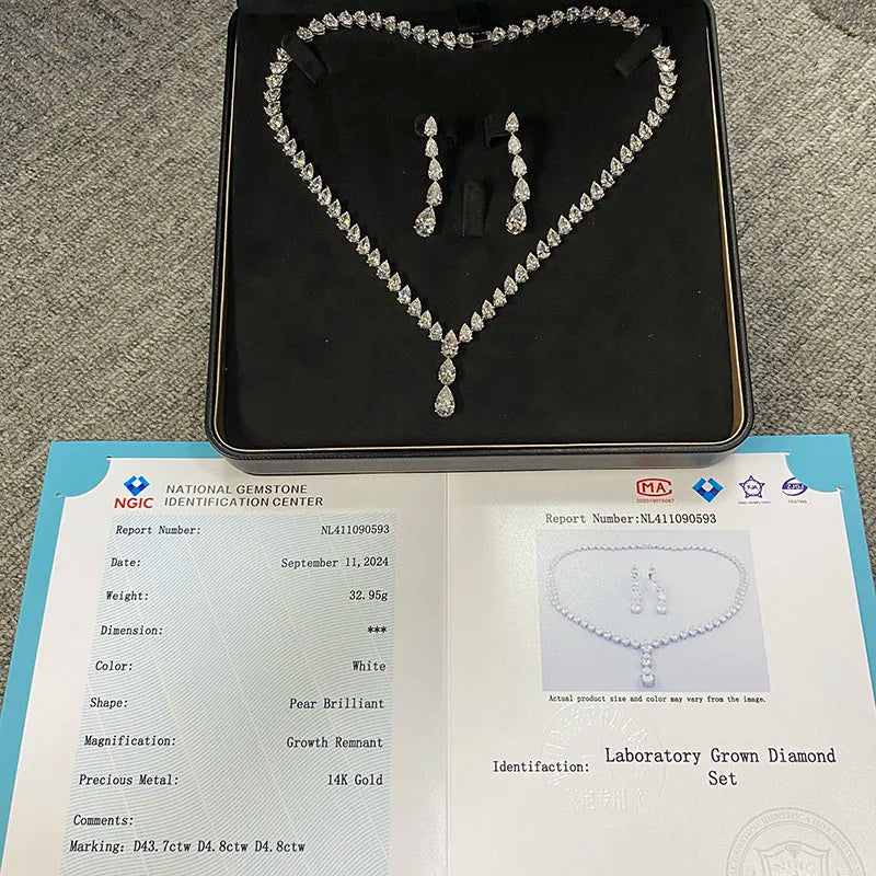 A heart-shaped diamond necklace and matching drop earrings displayed on a black jewelry box, with an open gemstone certification report placed below on a gray carpet background.