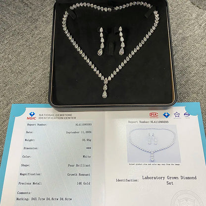 A heart-shaped diamond necklace and matching drop earrings displayed on a black jewelry box, with an open gemstone certification report placed below on a gray carpet background.