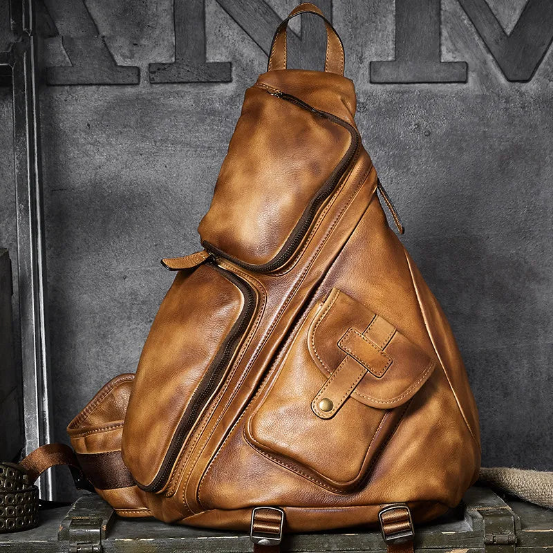 A distressed brown leather duffel-style backpack with multiple zippered compartments and a front pocket, displayed on a rustic wooden surface against a dark textured wall.