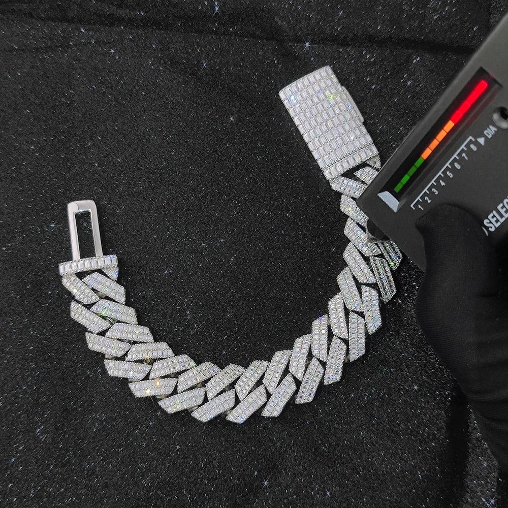 A silver-toned chain bracelet paved with clear stones, displayed on a black textured surface next to a black gloved hand holding a measuring device.