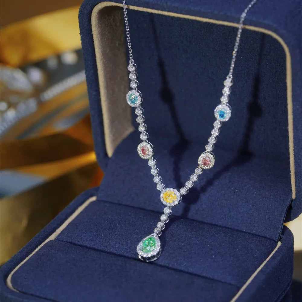 A silver-toned V-necklace with colorful gemstone accents, displayed inside an open dark blue velvet jewelry box.