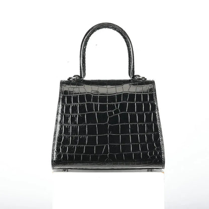 A structured black crocodile-embossed leather handbag with a top handle, displayed against a plain white background.