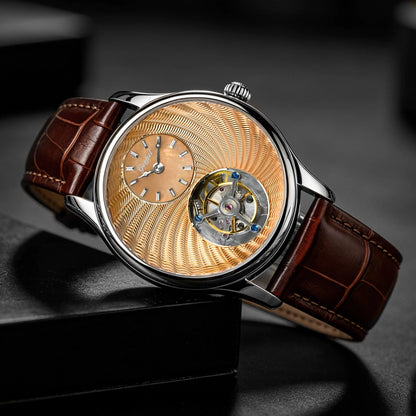 A luxury mechanical watch with a brown leather strap, a silver-toned case, and a distinctive gold-toned textured dial featuring a visible tourbillon movement through an open center.