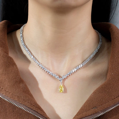 Necklace with a yellow gemstone pendant worn by a person in a brown jacket.