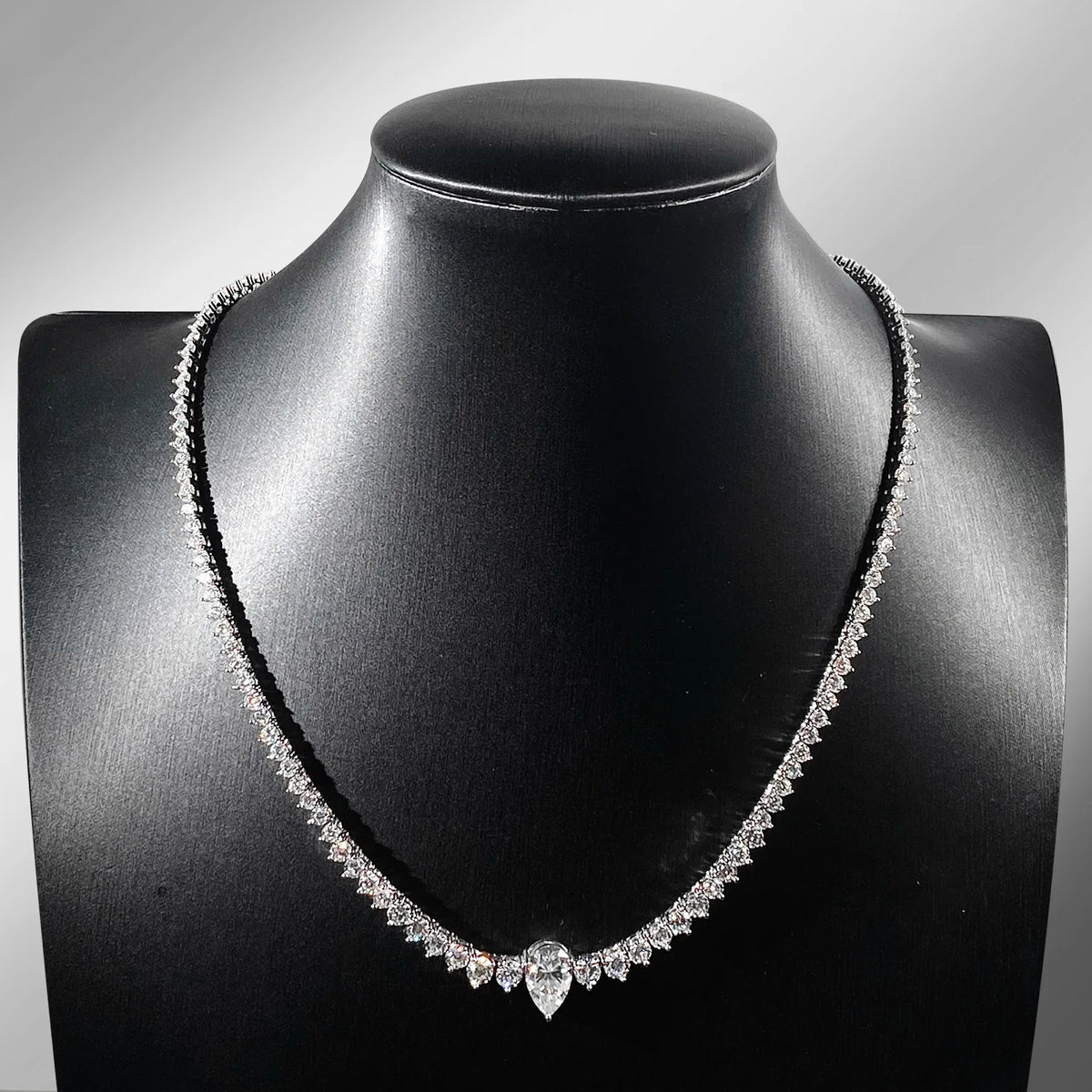 Diamond necklace on a black mannequin bust against a gray background