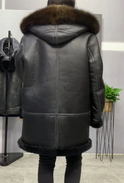A person shown from the back wearing a black leather hooded coat with a brown fur-trimmed hood and hem, standing indoors in a store-like setting.
