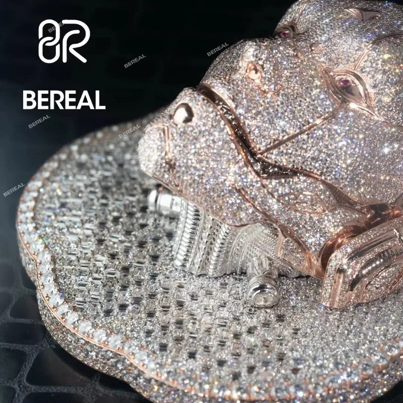 A close-up of a BEREAL brand hip-hop style speaker or decorative sculpture covered in sparkling rhinestones, featuring a rose gold-toned head resting on a silver-toned round base against a dark background.