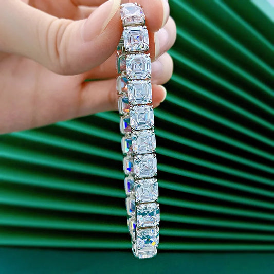 Diamond bracelet held by a hand against a green background