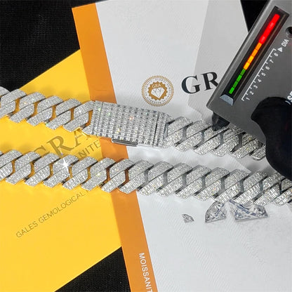 A close-up of a diamond-encrusted silver chain bracelet laid across branded papers and a yellow-and-white box, with a small handheld device on the right.