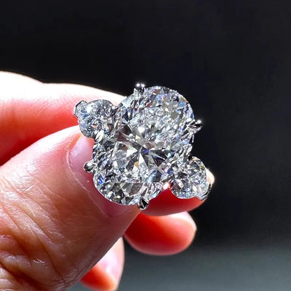Diamond ring held in a hand against a dark background