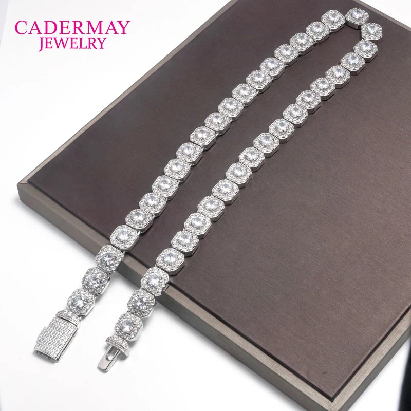 A silver-toned diamond-encrusted tennis bracelet displayed on a dark brown presentation box, with the brand name 'CADERMAY JEWELRY' in pink text in the upper left corner.