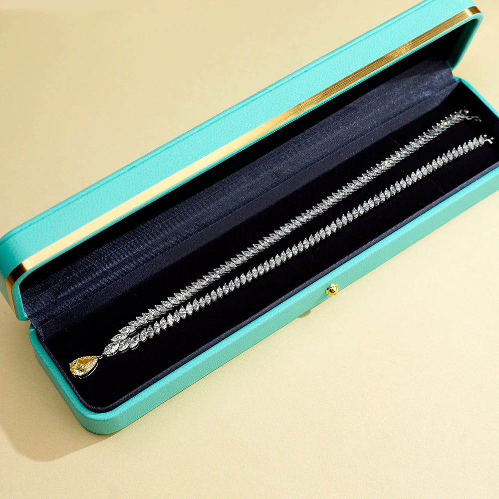 Silver bracelet with a yellow gemstone in a turquoise jewelry box on a beige background