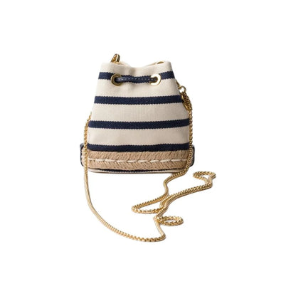 A small bucket-style crossbody bag with navy blue and cream horizontal stripes, a braided jute trim, and a gold-tone chain strap, shown on a plain white background.