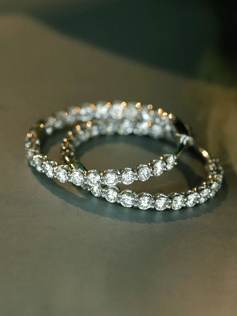 A close-up of a double tennis bracelet with round-cut clear stones in a silver-toned setting, resting on a dark gray surface.