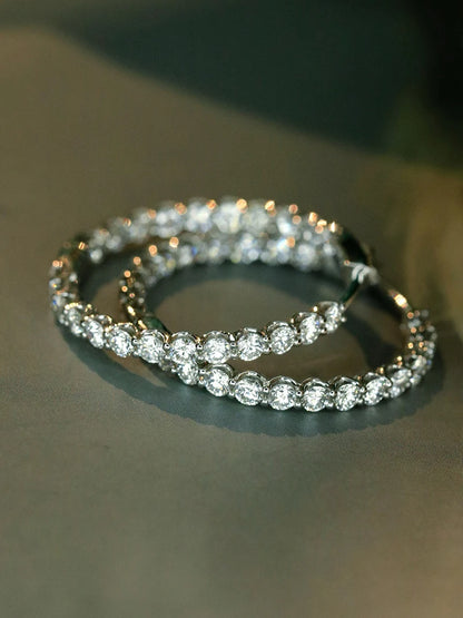A close-up of a double tennis bracelet with round-cut clear stones in a silver-toned setting, resting on a dark gray surface.
