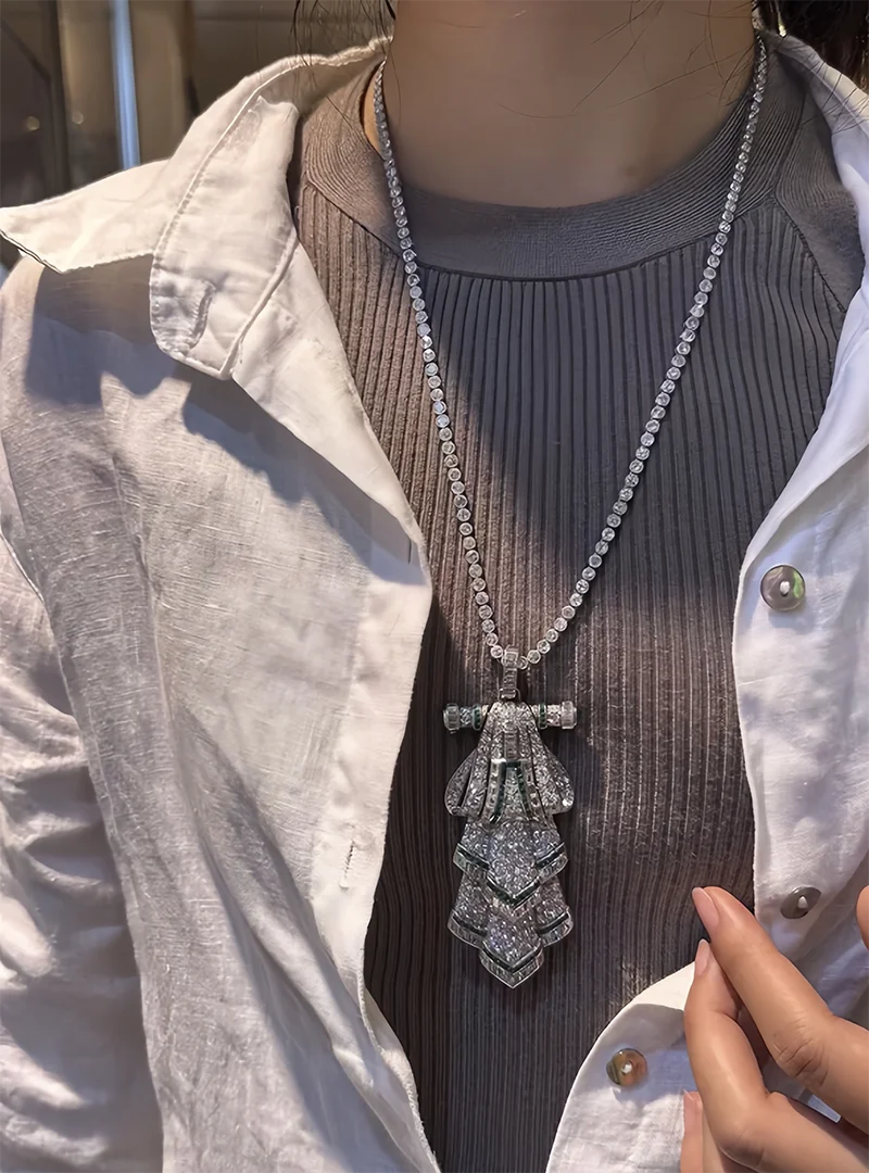 Person wearing a long, ornate necklace with a detailed pendant.