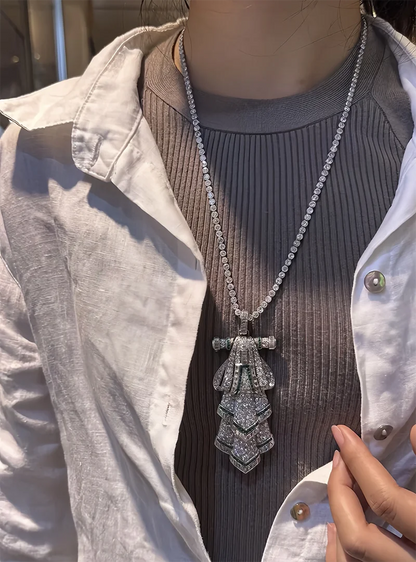 Person wearing a long, ornate necklace with a detailed pendant.