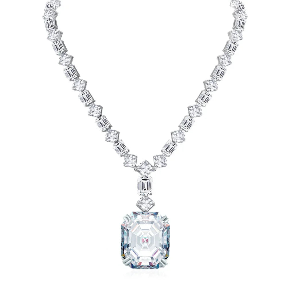 A silver-toned necklace featuring a large rectangular emerald-cut clear gemstone pendant, with a matching chain of smaller emerald-cut and baguette-cut clear stones, shown on a plain white background.