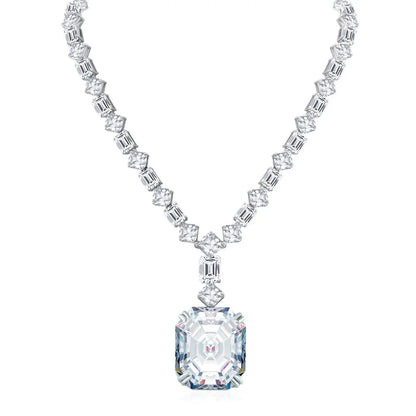 A silver-toned necklace featuring a large rectangular emerald-cut clear gemstone pendant, with a matching chain of smaller emerald-cut and baguette-cut clear stones, shown on a plain white background.