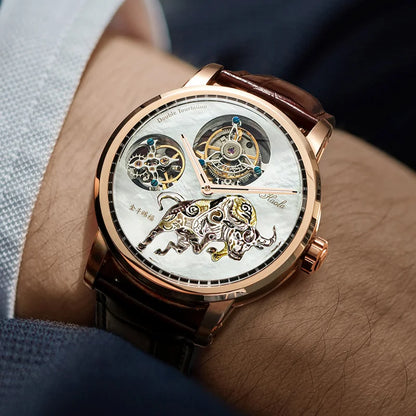 A close-up lifestyle shot of a men's skeleton watch on a wrist. The watch features a rose gold case, a white mother-of-pearl dial with a detailed gold and silver bull skeleton design, and a brown leather strap.