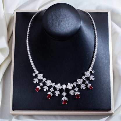 Diamanté necklace with red gemstones on a black stand against a white fabric background