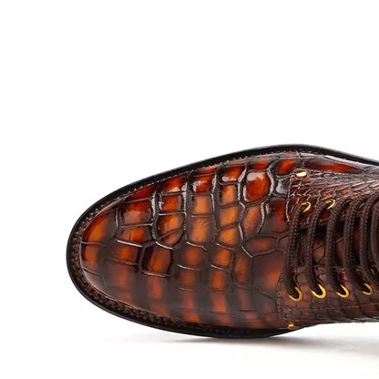 Close-up of the toe and side of a brown crocodile-embossed lace-up boot on a white background.