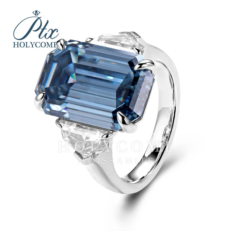 A silver ring featuring a large, faceted blue emerald-cut center stone and smaller clear accent stones, shown on a white background with a 'Ptc HOLYCOMME' watermark.
