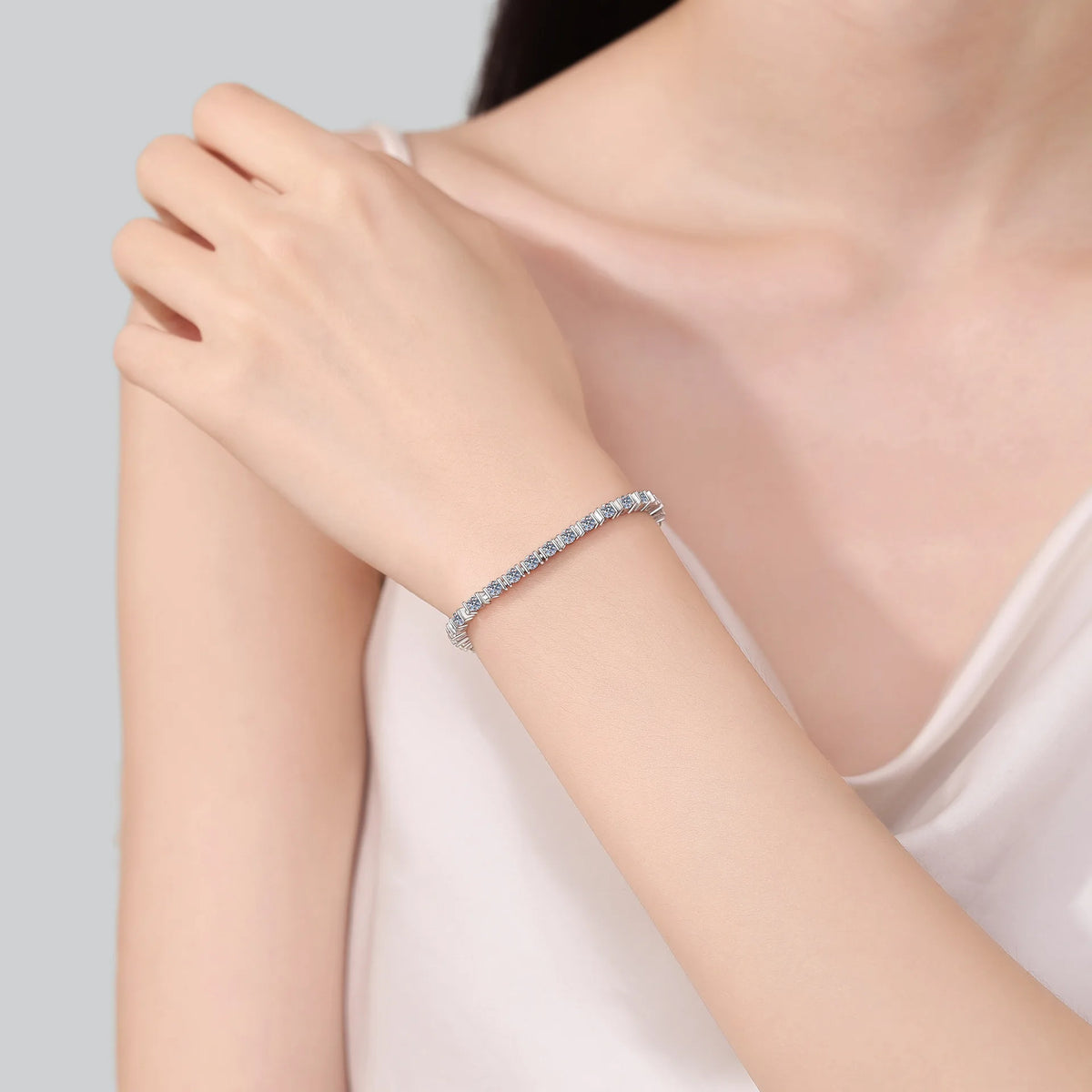 Silver bracelet on a person's wrist with a plain background