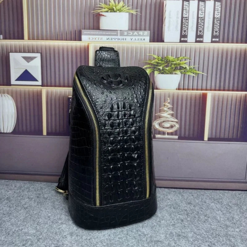 A black crocodile-embossed leather backpack with gold-tone zippers, standing upright on a gray carpet in front of a wooden bookshelf with plants and decorative items.