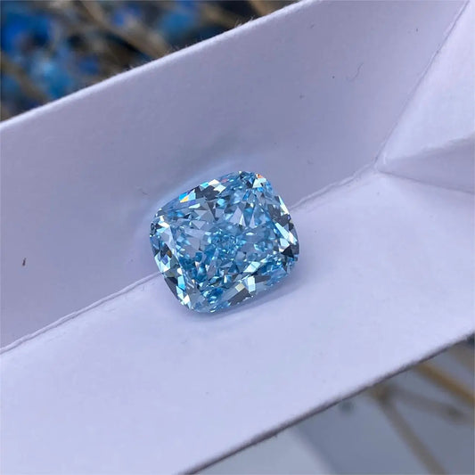 A cushion-cut light blue gemstone, likely a diamond, resting on a white textured surface.