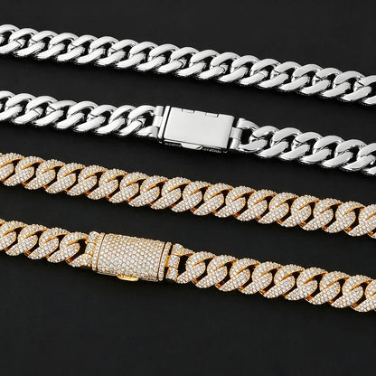 Four Cuban link chain necklaces arranged diagonally on a black background, including two silver-toned and two gold-toned chains, with three of them featuring pavé-set rhinestones.