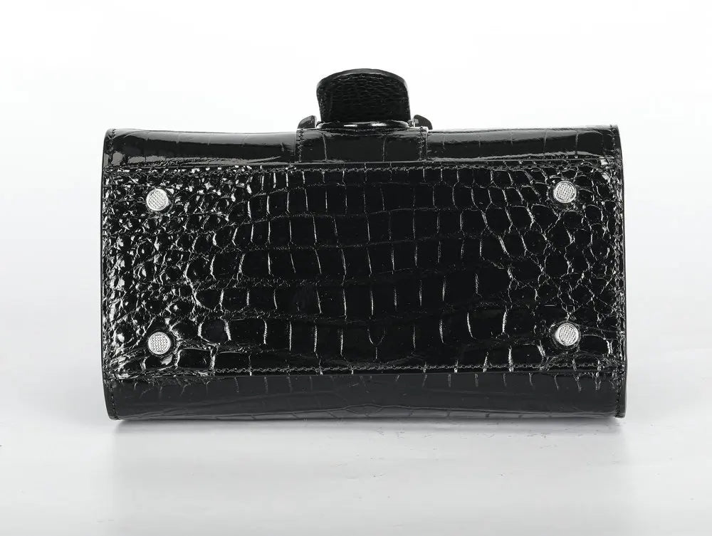 A black crocodile-embossed clutch bag with a glossy finish, featuring silver-tone metal studs and a black fabric wristlet strap, shown against a plain white background.