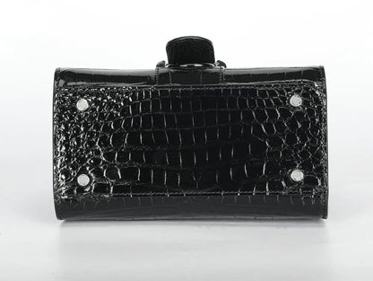A black crocodile-embossed clutch bag with a glossy finish, featuring silver-tone metal studs and a black fabric wristlet strap, shown against a plain white background.