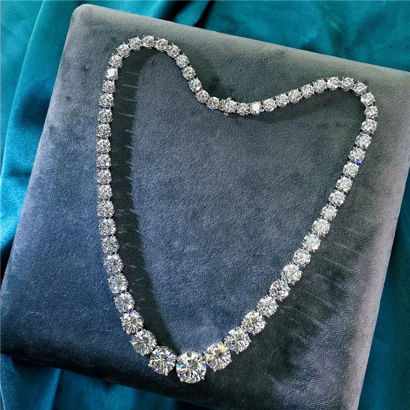 Diamond necklace shaped like a heart on a gray cushion with teal fabric background