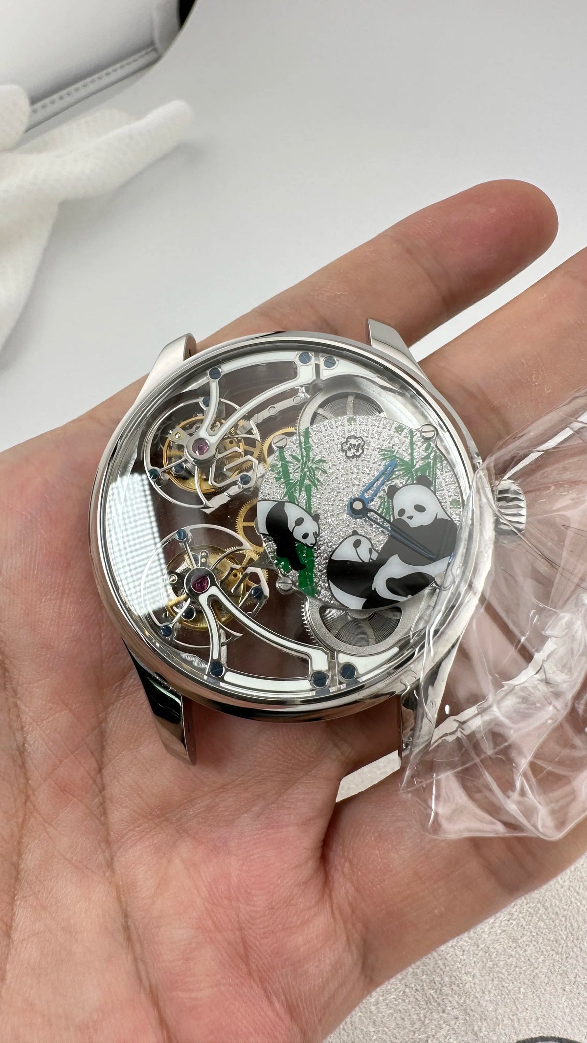 Close-up of a mechanical watch with panda design held in a hand.
