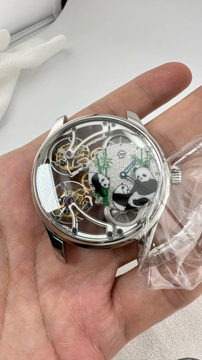 Close-up of a mechanical watch with panda design held in a hand.