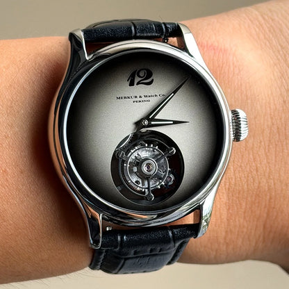 Luxury watch with black leather strap and visible mechanical components on a wrist.