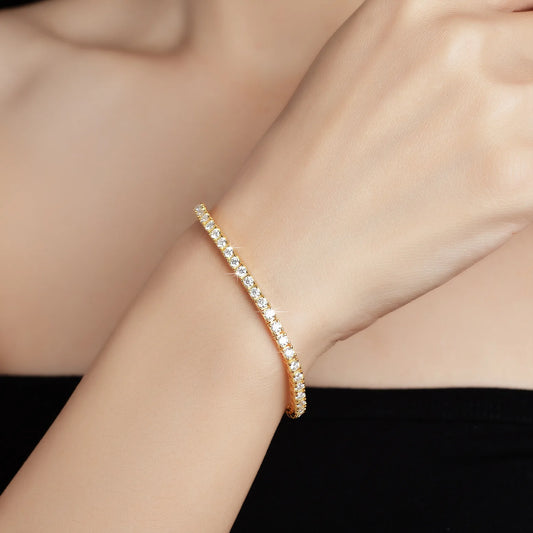Gold bracelet with clear stones on a person's wrist against a black background