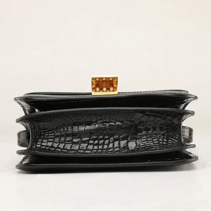 Black crocodile-embossed leather clutch bag with a gold-tone metal clasp, shown from the front on a light gray background.
