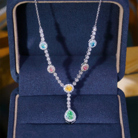 A silver-toned necklace with multiple colorful gemstone accents, displayed inside an open dark blue jewelry box.
