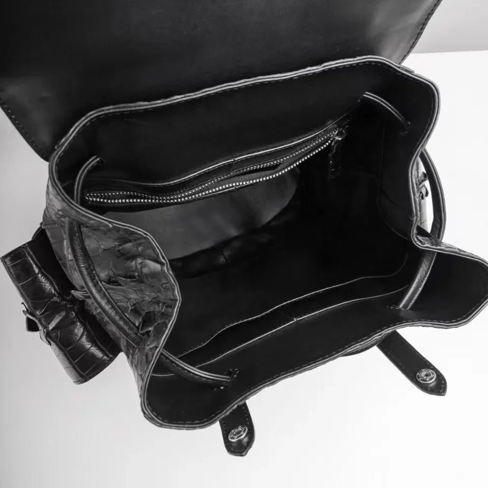 Black textured leather handbag shown open from above, revealing a spacious interior with a zippered pocket and dark lining on a white background.