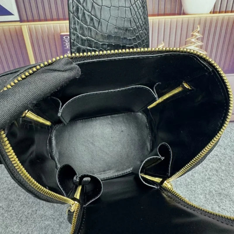 Close-up of the interior of a black handbag with gold-tone zippers and hardware, showing the lining and compartment structure.
